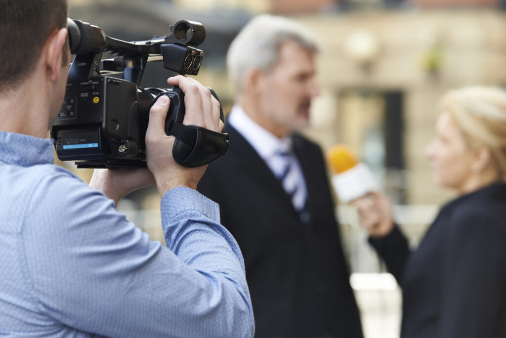 Medietræning interview tv interview øvelse budskab strategier kropssprog En kameramand filmer et interview i en udendørs indstilling, Medietræner og erfaren journalist Anna Foss hjælper med budskabsudvikling og performance, så du bliver tryg når du skal i medierne